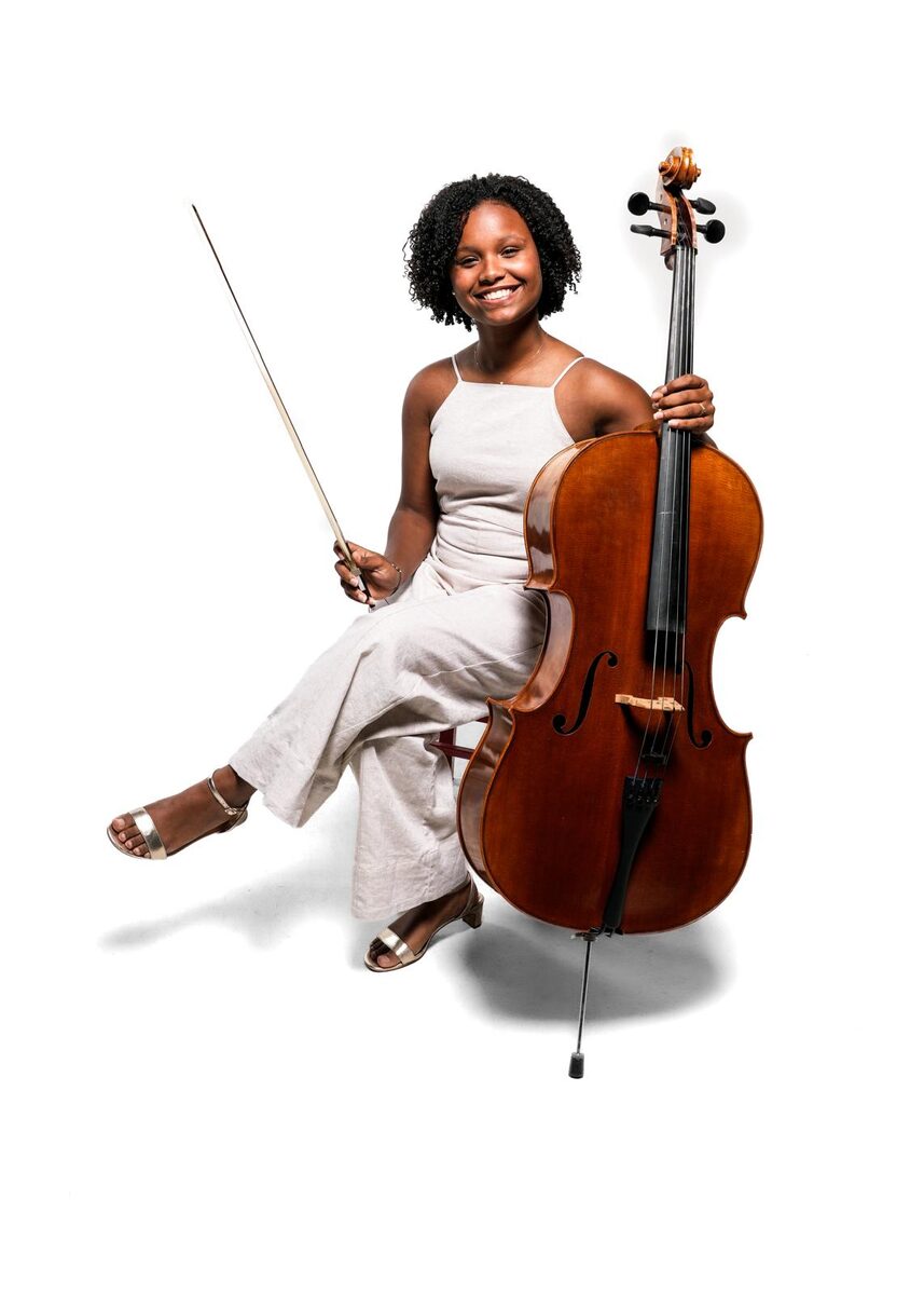 Sara con su violonchelo, arco en alto y sonriendo